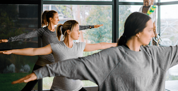 Gravid kvinne som praktiserer yoga med andre kvinner